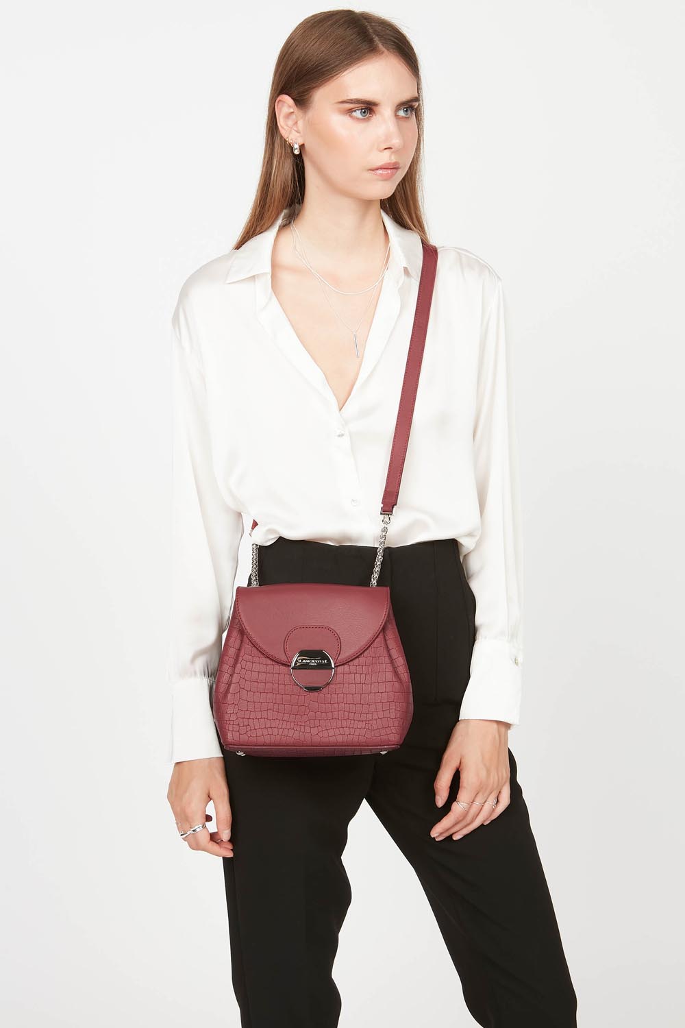 Lancaster Borsa a tracolla con patta e chiusura Pia Camel – Il trotteur Pia bordeaux si porta a tracolla con una camicia bianca e pantaloni neri.