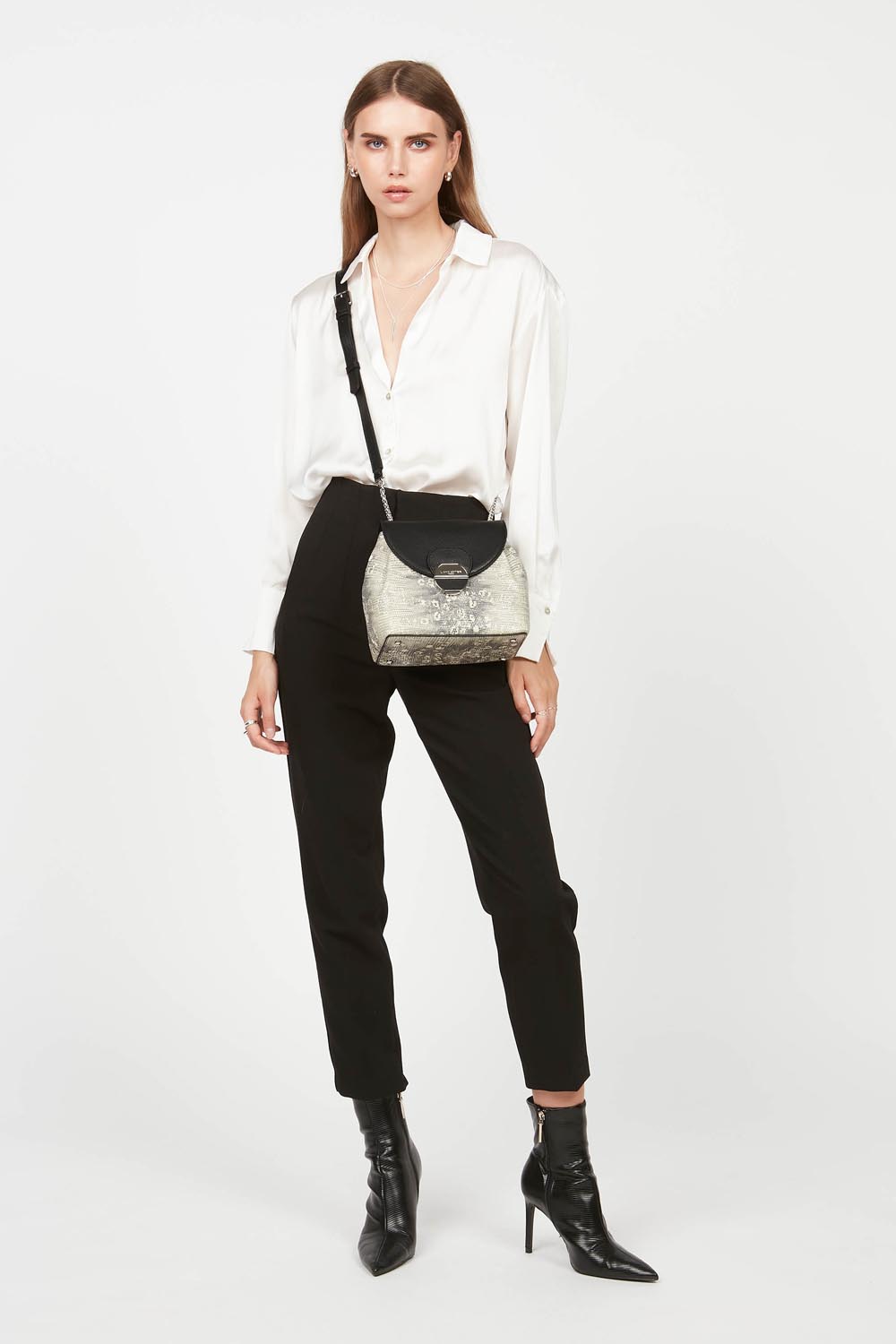 Lancaster Borsa a tracolla con patta e chiusura Pia Camel – Camicia bianca e pantaloni neri per il trotteur Pia portato a tracolla.