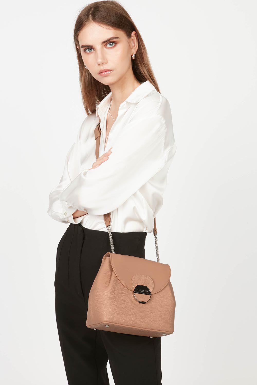 Lancaster Borsa a tracolla con patta e chiusura Pia Camel – La borsa Pia si porta a spalla con una camicia bianca e pantaloni neri.