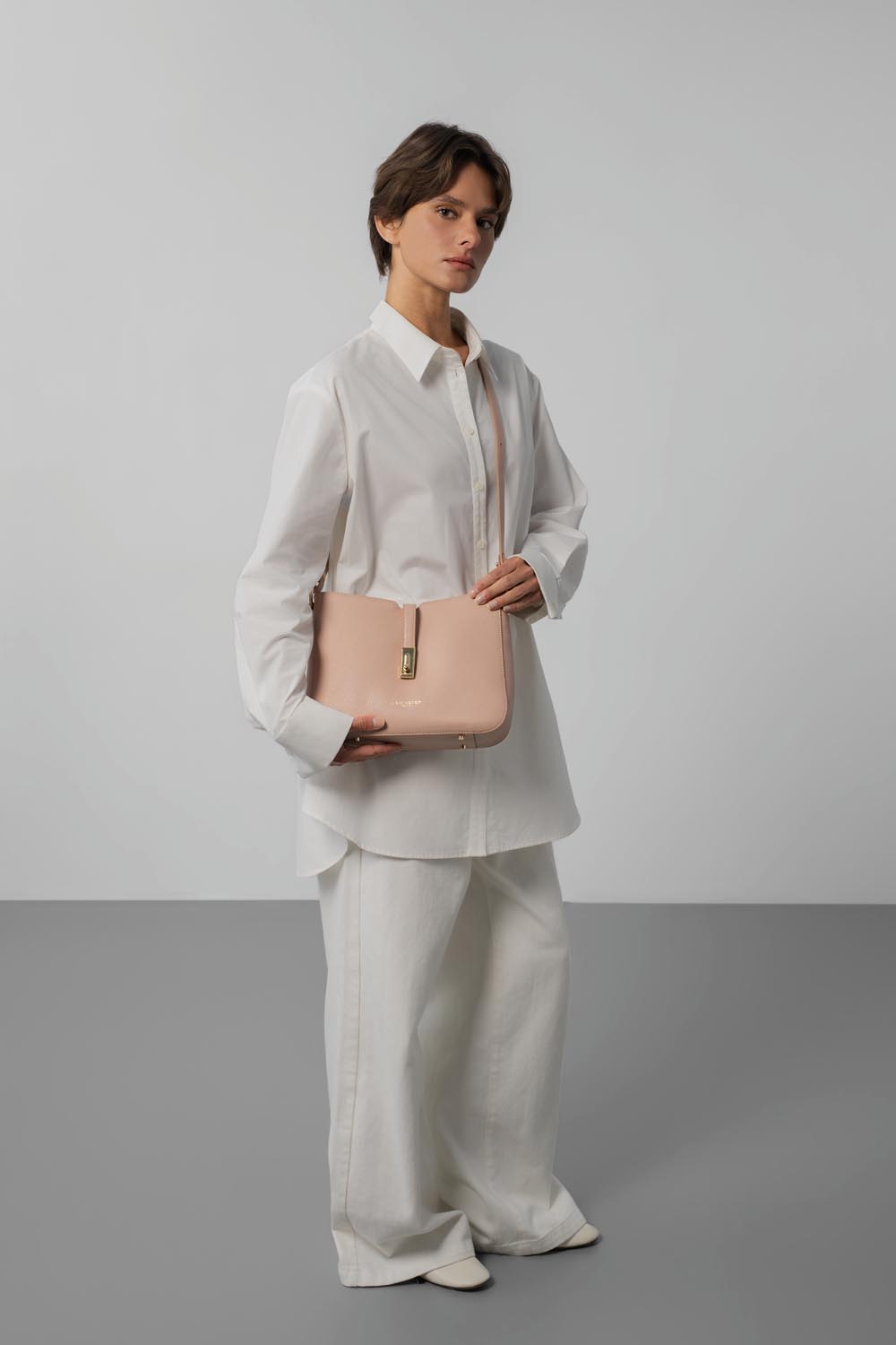Lancaster Sac besace Zippé L Milano Horizon Sable – Glissée à l’épaule, la besace Milano Horizon complète une chemise blanche et un pantalon ample assorti.