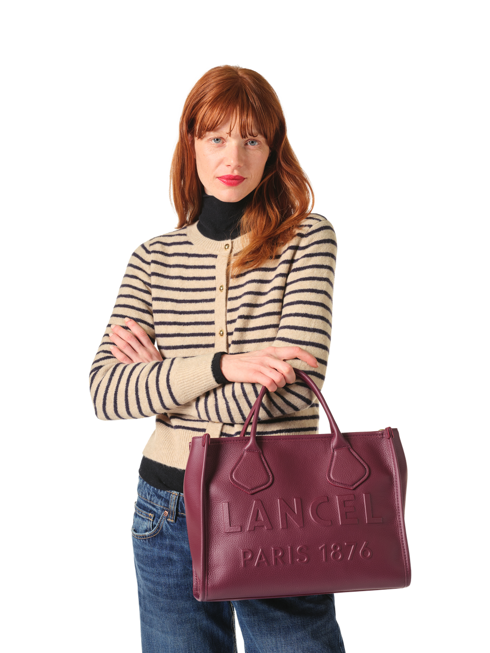 Lancel cabas M Jour De violet tenu à la main avec un cardigan rayé et un jean bleu.