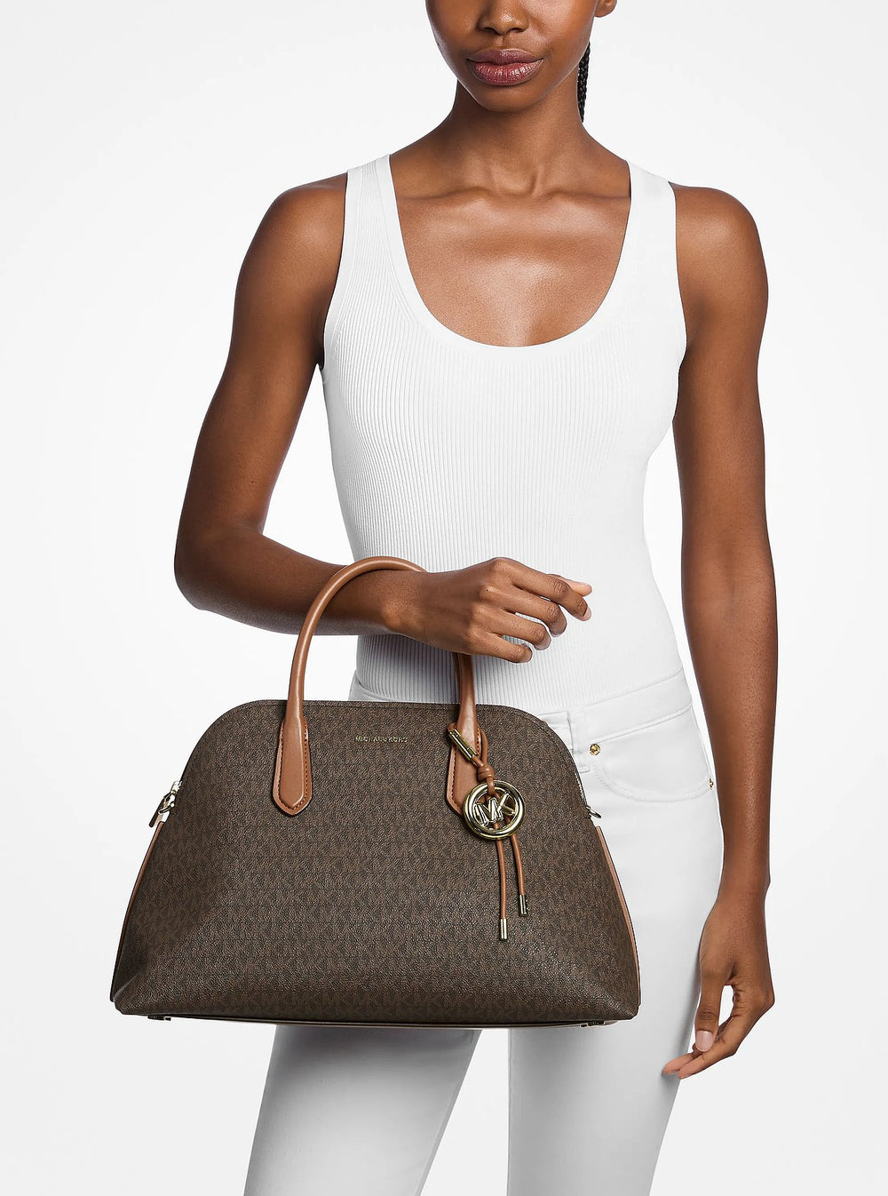 Michael Kors Freddie-Shopper a Braun, an der Hand gehalen, mat engem wäissen Top an enger wäisser Box.