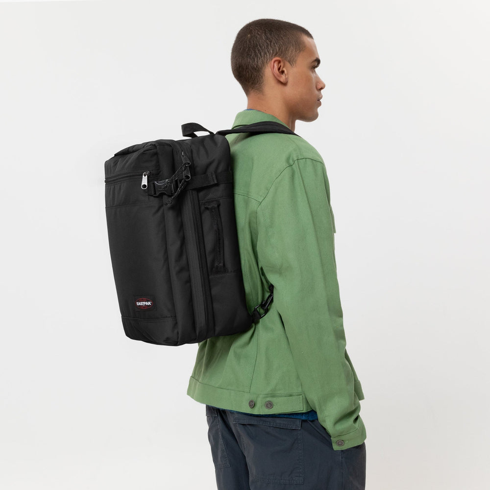 Eastpak czarny plecak Transit’r Pack noszony na plecach, z zieloną kurtką i granatowymi spodniami.